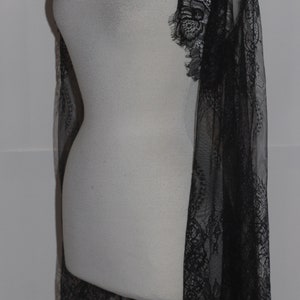 May include: A black lace shawl with a delicate floral pattern. The shawl is sheer and lightweight, and it would be perfect for adding a touch of elegance to any outfit.