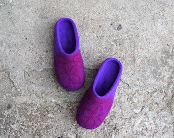 May include: A pair of purple felt slippers with a floral design. The slippers are made of a soft, comfortable material and have a comfortable fit.