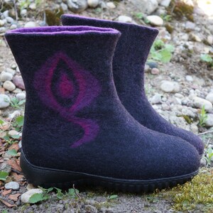 May include: A pair of black felt boots with a purple and pink design. The boots have a rubber sole and a rounded toe.