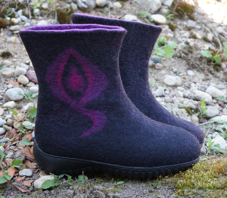 May include: A pair of black felt boots with a purple and pink design. The boots have a rubber sole and a rounded toe.