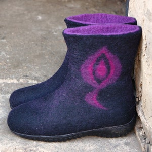May include: A pair of black felt boots with a pink and purple design. The boots have a rounded toe and a thick sole.