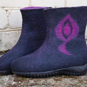 May include: A pair of black felt boots with a pink design on one boot. The boots have a rubber sole.