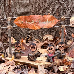 Puede incluir: Una banda de madera caprichosa, "The Knotty Knotters", actúa en un escenario de madera. Los miembros de la banda están hechos de cáscaras de nuez y ramitas, con una pancarta de hojas encima. La escena está ambientada entre hojas caídas.