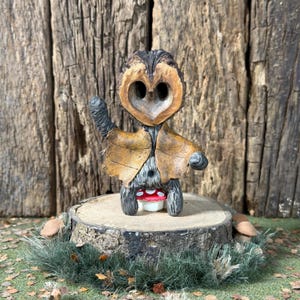 May include: A handcrafted woodland creature figurine made from natural materials. The figure has a walnut shell head, leaf-like details, and a mushroom base. The creature stands on a tree stump, surrounded by greenery, creating a charming, rustic aesthetic.