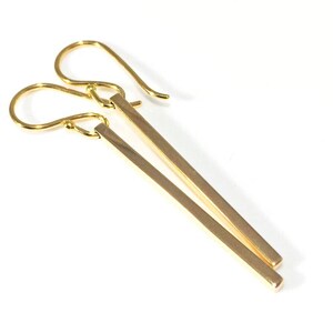 Square gold bar earrings on a white background.