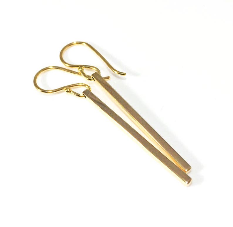 Square gold bar earrings on a white background.