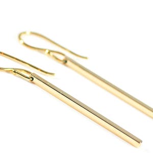 Square gold bar earrings on a white background.