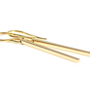 Square gold bar earrings on a white background.