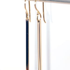 Square gold bar earrings on a white background, shown hanging.