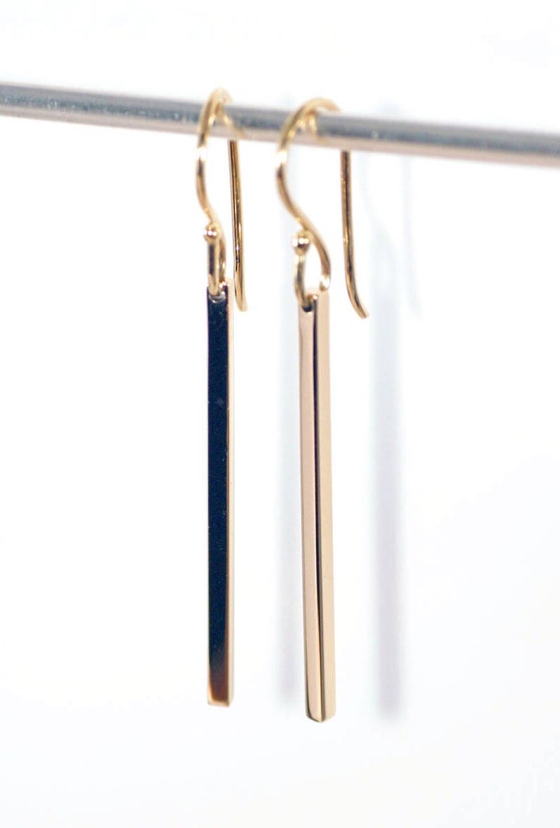 Square gold bar earrings on a white background, shown hanging.