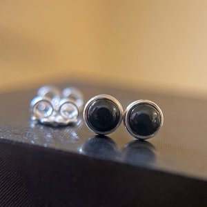 May include: A pair of black onyx stud earrings with silver settings.