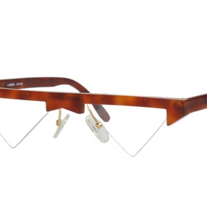 以下が含まれることがあります： 鼈甲柄の三角形のフレームと金色のアクセントが付いた眼鏡です。