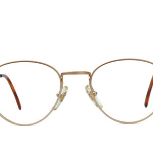 May include: A pair of gold-toned metal eyeglasses with round frames and brown plastic temple arms.