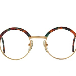 May include: Round gold-rimmed eyeglasses with a tortoiseshell pattern on the frame.