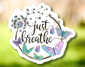 May include: A white sticker with a floral and butterfly design. The sticker features the words "just breathe" in a cursive font, surrounded by butterflies in shades of purple, teal, and pink. A dandelion is also included in the design.