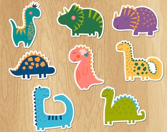 May include: A set of eight colorful dinosaur stickers with various designs, including a green triceratops, a purple stegosaurus, a blue ankylosaurus, a pink brachiosaurus, a yellow apatosaurus, a blue dinosaur with a crown, a green dinosaur with a blue stripe, and a green dinosaur with a blue stripe.