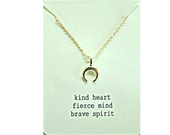 May include: Gold necklace with a crescent moon charm and a card that reads "kind heart fierce mind brave spirit"