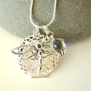 May include: Silver dragonfly charm necklace with a green glass bead and a filigree design.