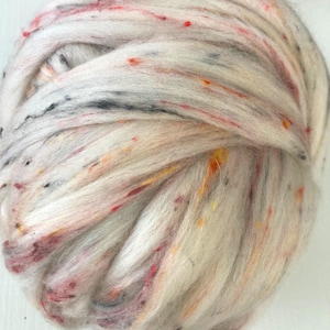 May include: A close-up of a ball of white yarn with flecks of red, orange, yellow, and black. The yarn appears soft and textured, ideal for knitting or crocheting projects. The colors create a speckled effect.