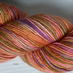 May include: A skein of multicolored yarn with shades of pink, orange, green, and purple. The yarn is called "Garden".