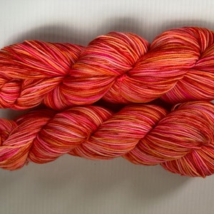 May include: A skein of yarn in a multi-colored stripe pattern of red, orange, pink, and white.