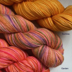 May include: Three skeins of yarn in shades of orange, pink, and purple. The yarn is labeled "Sunkiss", "Garden", and "Coral".
