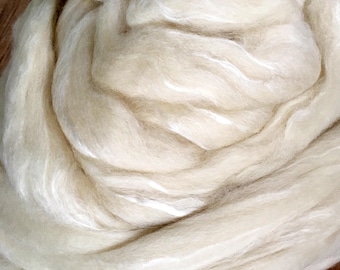 May include: A close-up of a large bundle of white wool roving. The wool is soft and fluffy, and it is perfect for spinning or felting.