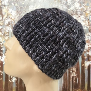May include: A dark gray knitted beanie with a textured pattern. The beanie is made of a soft, warm yarn and is perfect for cold weather.