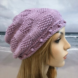 May include: A lavender knitted beanie with a textured pattern and small decorative beads around the brim.