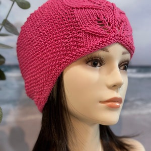 May include: A pink knitted hat with a lacy design. The hat is made with a soft yarn and has a comfortable fit.