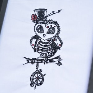 May include: Black and white embroidered design of a steampunk owl wearing a top hat with a red flower. The owl is perched on a branch with a chain and compass hanging below.