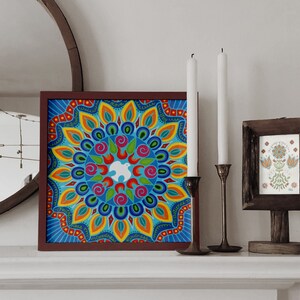 May include: A framed colorful mandala artwork with a white dove in the center. The mandala is surrounded by a border of text that reads "This is my masterpiece, kindness is my masterpiece". The artwork is hanging on a white wall with two candlesticks and a framed print of a floral design.