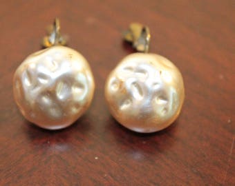 May include: A pair of pearl earrings with a textured surface and gold-toned metal clasps.