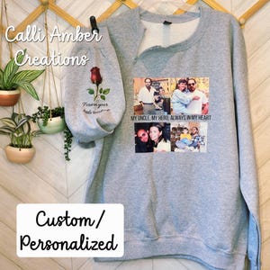 May include: A gray sweatshirt with a custom design. The design includes a rose graphic, the text "Forever your little rose", and a collage of photos. The text "My uncle, my hero, always in my heart" is also printed on the sweatshirt. The words "Custom/Personalized" are also visible.