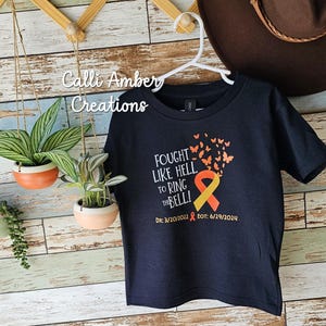 May include: Black t-shirt with a yellow and orange ribbon and butterflies. The text reads "Fought Like Hell To Ring The Bell!" with the dates "Dx: 3/20/2022 EOT: 6/29/2024".