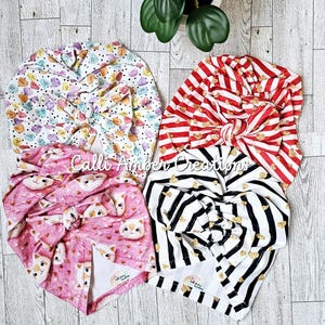 Può includere: Quattro fasce per capelli con diversi motivi e un fiocco in cima. Le fasce sono di vari colori e motivi, tra cui rosa, rosso, bianco e nero. Tutte le fasce sono legate con un fiocco in cima.