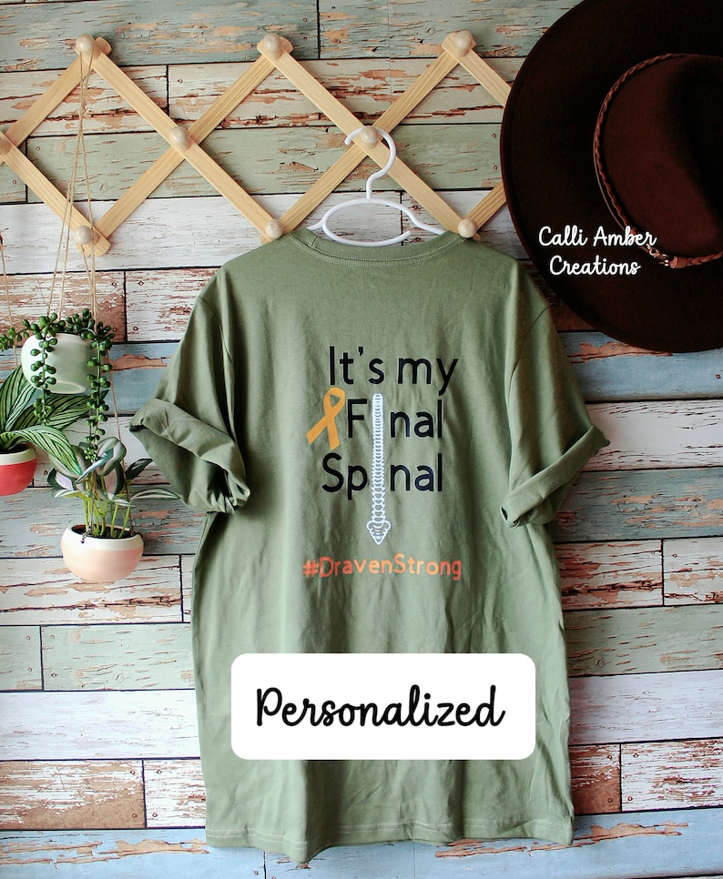 May include: A green t-shirt with the text "It's my Final Spinal #DravenStrong" and a stylised image of a spine. The text "Personalized" is printed below the design.