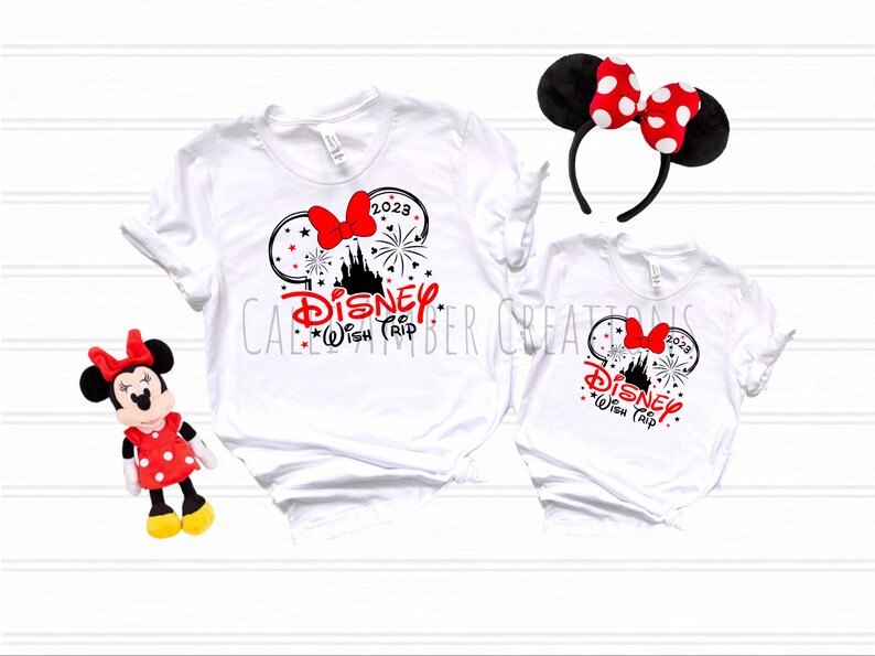May include: Two white t-shirts with a black and red graphic of Mickey Mouse ears, a castle, fireworks, and the text "Disney Wish Trip 2023".