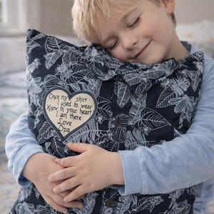 May include: A square throw pillow crafted from a dark navy blue button-down shirt with a white botanical leaf pattern. A heart-shaped patch is stitched onto the front, featuring the text: Once my shirt I used to wear Know in your heart I am there Love Opa.