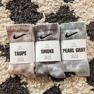 May include: Three pairs of socks in different colours: taupe, smoke, and pearl grey. Each sock has a white tag with the size, colour, and brand name "WH" printed on it.