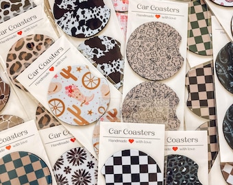 Könnte beinhalten: Eine Sammlung von Auto-Untersetzern mit verschiedenen Designs, darunter Blumen-, Karomuster-, Leoparden- und Kuhmuster. Die Untersetzer sind handgefertigt und tragen den Text "Car Coasters" und "Handmade with love".