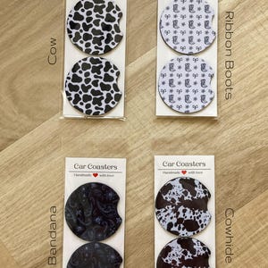 May include: Four sets of car coasters with different designs. The designs are cowhide, bandana, cow, and ribbon boots. Each set includes two coasters.