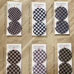 May include: Set of two car coasters with a checkered pattern in black, white, tan, and blue. The coasters are packaged in clear plastic and labeled "Car Coasters" with a heart and the text "Handmade with love".