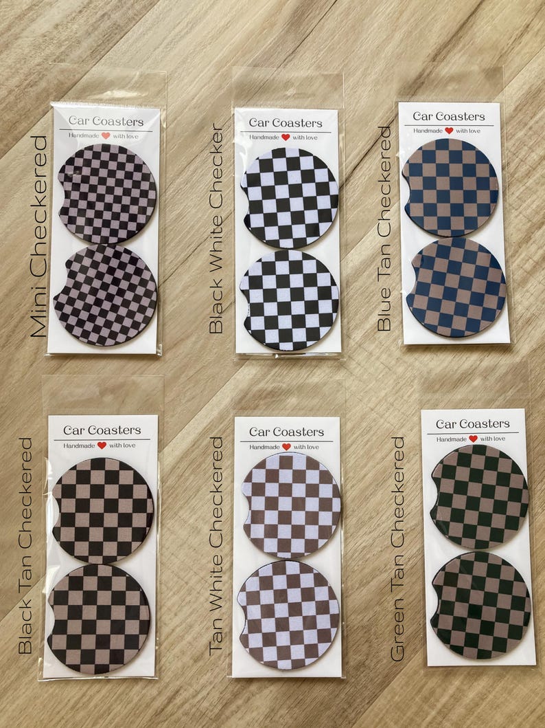 May include: Set of two car coasters with a checkered pattern in black, white, tan, and blue. The coasters are packaged in clear plastic and labeled "Car Coasters" with a heart and the text "Handmade with love".
