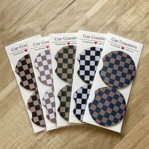 May include: Set of six handmade car coasters with a checkered pattern in black, white, green, and brown. The coasters are packaged in clear plastic bags with a label that reads "Car Coasters Handmade with love".