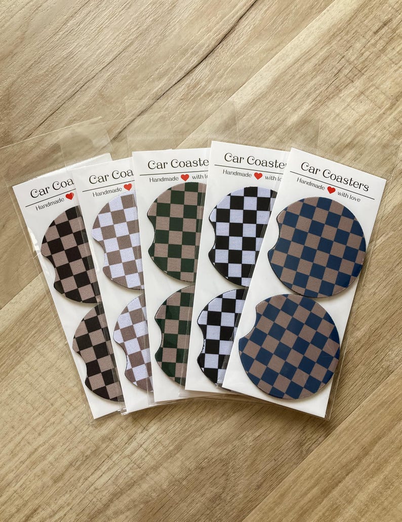 May include: Set of six handmade car coasters with a checkered pattern in black, white, green, and brown. The coasters are packaged in clear plastic bags with a label that reads "Car Coasters Handmade with love".
