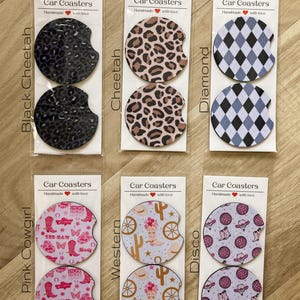 May include: Set of 10 car coasters with various designs, including cheetah print, diamond pattern, cowboy boots, and cacti. Each coaster is handmade and features the text "Car Coasters" and "Handmade with love".