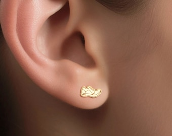 May include: Gold-toned shoe-shaped stud earrings. The earrings are small and delicate, and they feature a simple design.