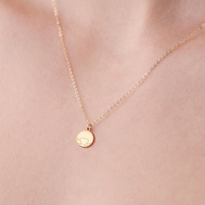 Könnte beinhalten: Eine zarte goldene Kettenkette mit einem kleinen runden Anhänger, der ein herzförmiges Wolkenmotiv zeigt.