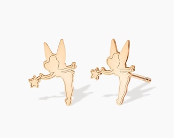 May include: A pair of gold-toned fairy stud earrings. Each earring features a delicate silhouette of a fairy with wings outstretched, holding a wand with a star at the end.
